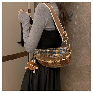Detail of vintage plaid chest bag with gold chain strap and cute plush charm pendant