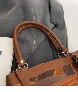 Close-up of vintage brown leather bag with wave stitching and silver metal buckle details