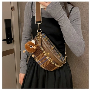 Detailed view of plaid crossbody chest bag featuring wide canvas strap and gold chain detail