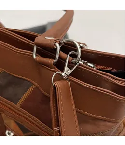 Detail of silver metal hook and fine stitching on a vintage brown leather handbag