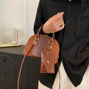 Brown crocodile embossed shell bag with coin purse on minimalist interior background