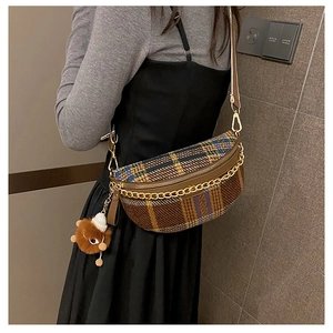 Detail of plaid crossbody bag with golden chain and brown plush toy charm on model
