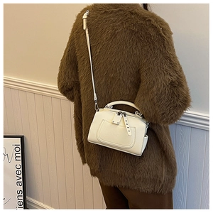 White textured leather Boston bag with silver hardware worn on a brown fur coat