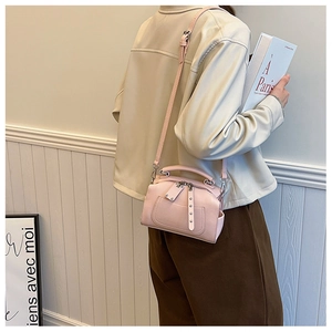 On-shoulder view of a stylish pink mini Boston bag with crossbody strap and leather texture