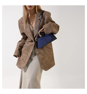 Detail of blue crocodile pattern handbag with unique gold metal handle and strap