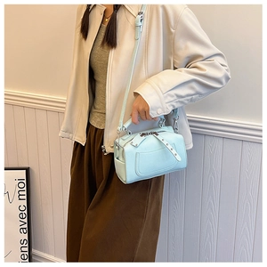 Close-up of light blue Boston bag with rivet tassel and textured leather details