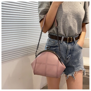 Pink leather shell bag with quilted stitching shown worn cross-body on a model