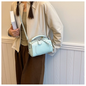 Chic light blue pebble leather boston bag styled with a beige jacket and brown trousers