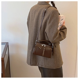Close-up of retro brown leather shoulder bag with metallic studs and handle details