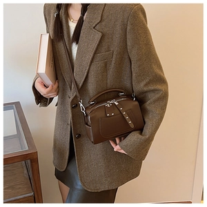 Close-up of brown vintage leather Boston bag with metal rivet details and top handle