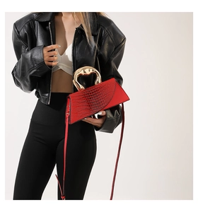 Detail of red crocodile texture handbag featuring a large round gold metal handle