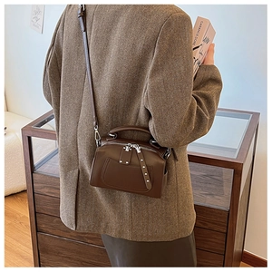 Brown vintage leather shoulder bag with top handle and silver rivets on wool blazer
