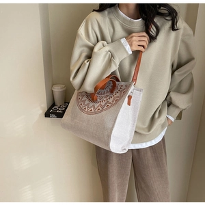 Detail of printed canvas tote bag featuring brown leather handles and adjustable shoulder strap