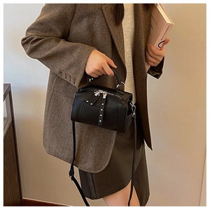 Detail of black Boston bag with silver studs and double zippers shown with a textured blazer