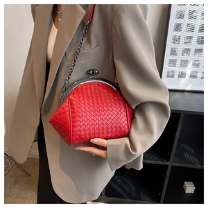 Detail of red woven leather shell bag with black metal clasp and chain strap