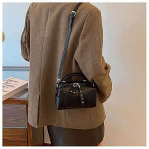 Close-up of black leather retro shoulder bag with silver studs and zipper detail