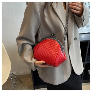 Detail of red woven shell bag with metal chain strap worn on a gray blazer suit