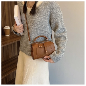 Detail of a brown lychee pattern leather Boston bag showing silver rivet zipper and handle