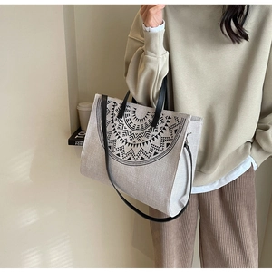 Close-up of beige canvas tote bag featuring ethnic geometric patterns and leather handles