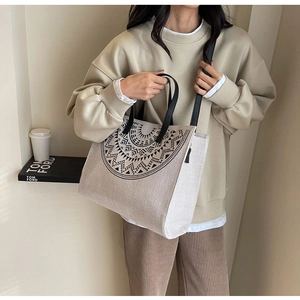 Close-up of beige linen tote bag featuring black geometric pattern and leather handles