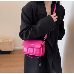 Detail of rose red rectangular crossbody bag with embossed 3D square patterns and silver logo