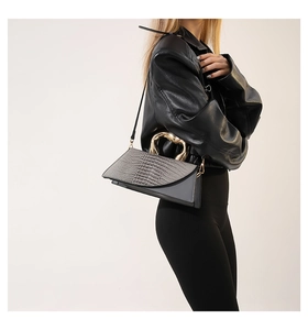Detail of grey crocodile pattern texture and golden heart-shaped metal handle on handbag