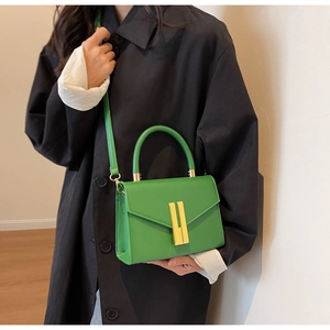 Detail of bright green leather handbag featuring distinctive parallel gold metal buckles