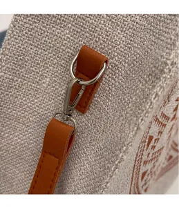 Close-up of durable silver metal hook and brown leather strap on linen tote bag