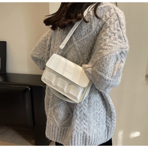 Detail of white leather shoulder bag with unique chocolate-style embossed texture