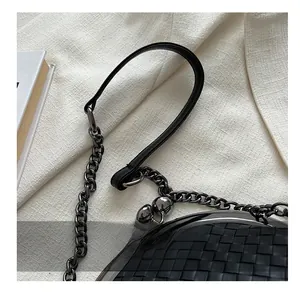 Close-up of woven black leather texture with gunmetal chain and comfortable handle strap