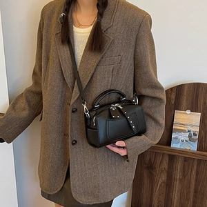 Retro black Boston handbag with silver rivets and shoulder strap on a fashion model