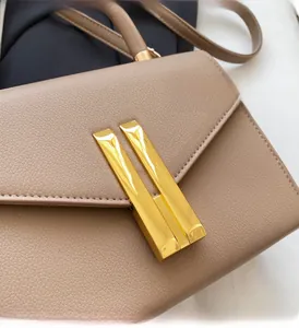 Detailed macro view of beige lychee grain leather and shiny gold metal buckle hardware