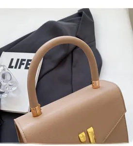 Detail of lychee pattern leather bag with thick cylindrical handle and gold metal buckle