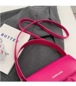 Detail of rose red crossbody bag with Fashion & Bags lettering and adjustable strap