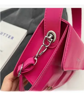 Close-up of silver rotating hook and stitching detail on a rose red square handbag