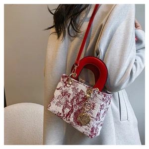 Detail of embroidered tote bag with red Toile de Jouy pattern and gold heart charm