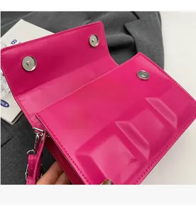 Detail of rose red PU leather handbag featuring square embossed texture and silver magnetic clasp