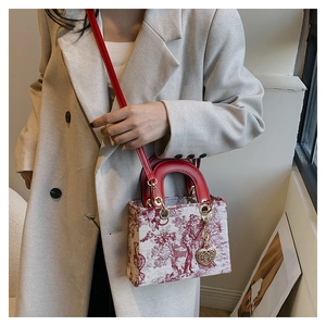Detail of red Toile de Jouy patterned handbag with leather handles and heart charm