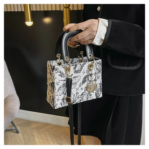 Detail of luxury embroidered handbag with floral patterns and gold metal charm