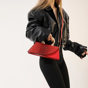 Elegant red crocodile pattern handbag with gold handle worn by model in leather jacket