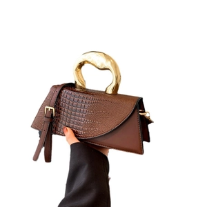 Dark brown crocodile-patterned handbag with asymmetric geometry and golden metal handle