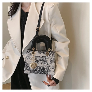 Close-up of Toile de Jouy tiger print canvas bag with gold heart charm and black handle