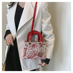 Detail view of the red embroidered handbag with heart charm and crossbody strap