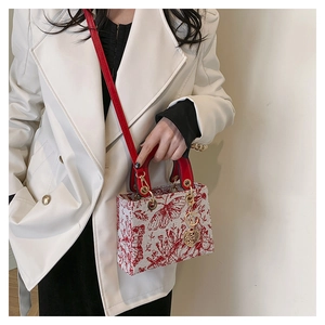 Detail of red and white embroidered handbag with butterfly pattern and heart pendant