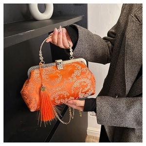 Detail of orange brocade handbag with gold floral embroidery and tassel charm