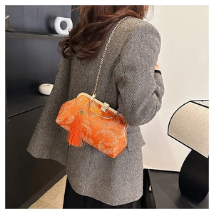 Détail du sac brodé orange avec motifs floraux et chaîne dorée à pompons