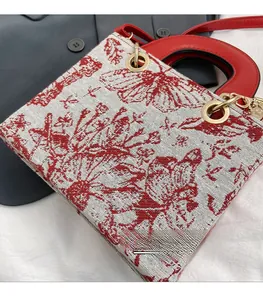 Close-up of floral butterfly embroidery and gold metal rings on a white luxury tote bag