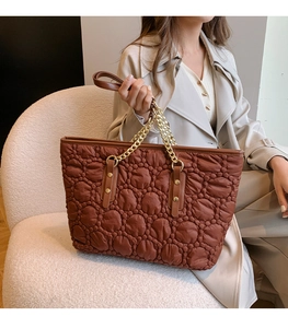 Dettaglio della borsa tote trapuntata marrone scuro con catena dorata e manico in pelle