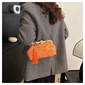 Detail of orange satin evening bag with gold embroidery and decorative tassel