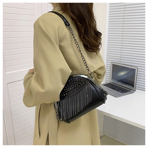 Detail einer schwarzen Tasche mit Nieten und langen Metallfransen an einem Model